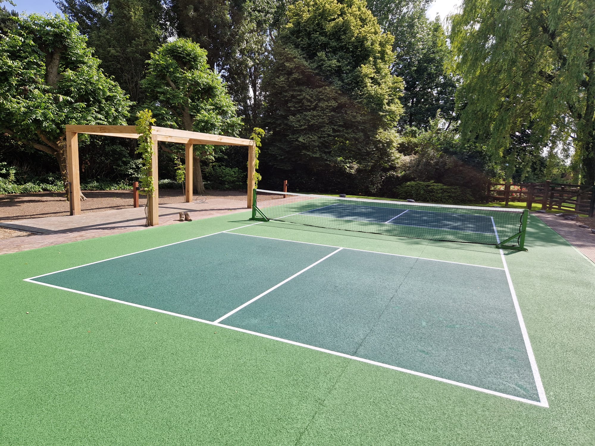Een groene pickleball baan omringd door bomen.