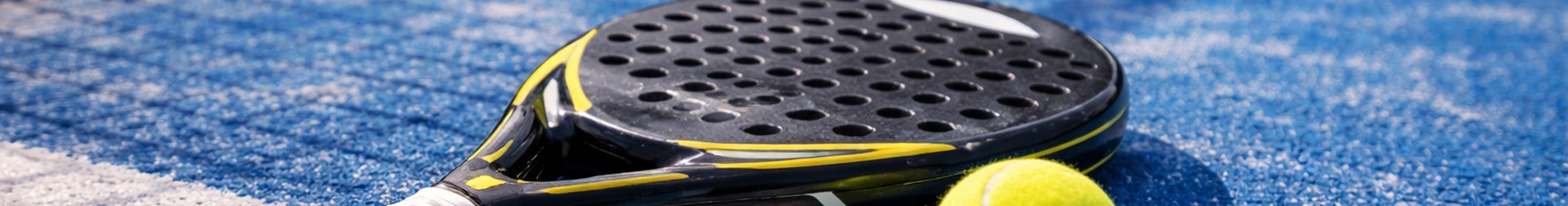 Padelracket en bal op een padelbaan
